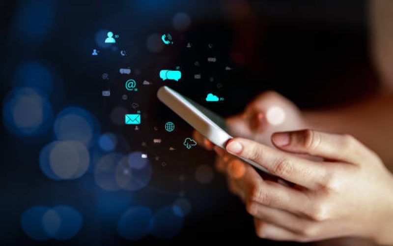 Woman using smartphone with multimedia digital icons on blurred background