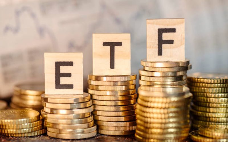 Several stacks with coins and the term ETF and a chart with stock prices.